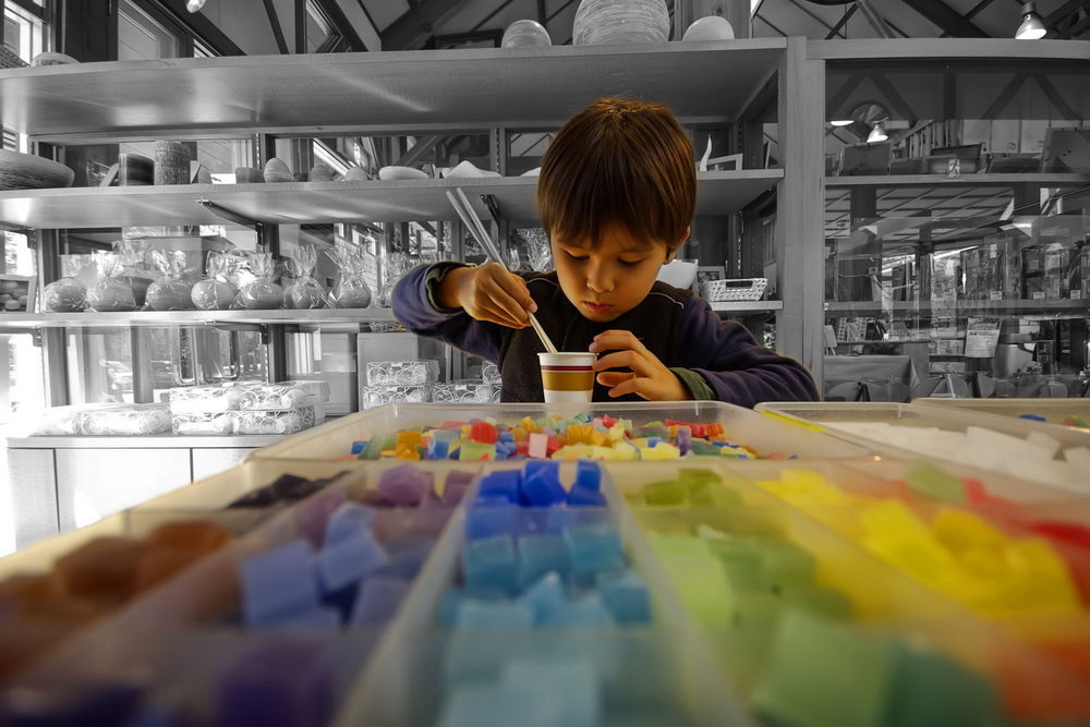 Обои для рабочего стола Мальчик собирает палочками разноцветные кубики в стакан