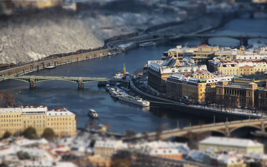 Обои на рабочий стол Город Прага / Prague / с видом на реку Влтава / Vltava / с проходящими по ней кораблями на фоне автомобильного моста и многоэтажных домов, с эффектом тилт шифт / tilt shift