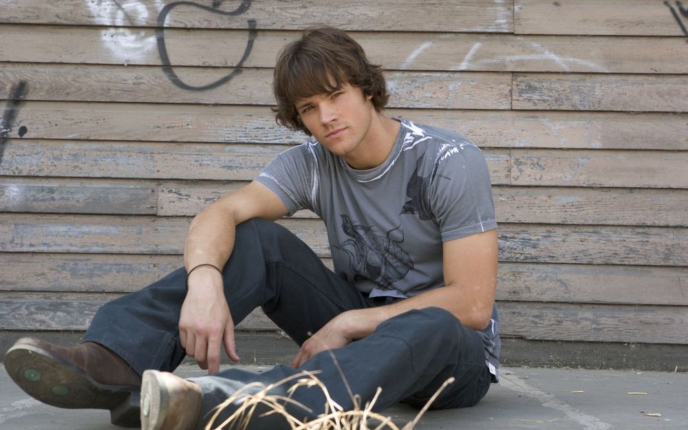 Обои для рабочего стола Джаред Падалеки / Jared Padalecki сидит у деревянной стены