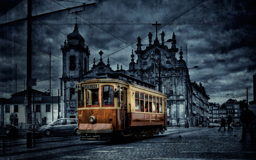 Обои для рабочего стола Желто-коричневый трамвай движется по сумеречному городу Порту, Португалия / Porto, Portugal на фоне старой церки Карму / Igreja do Carmo
