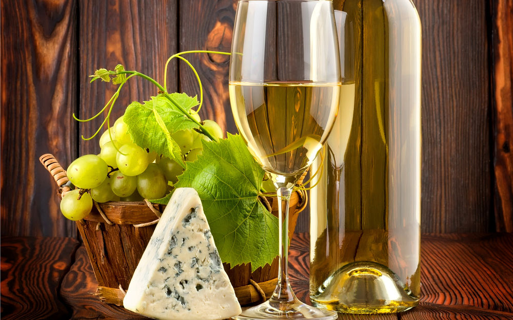 Обои для рабочего стола На столе стоит бутылка белого вина с кусочком сыра и гроздью винограда