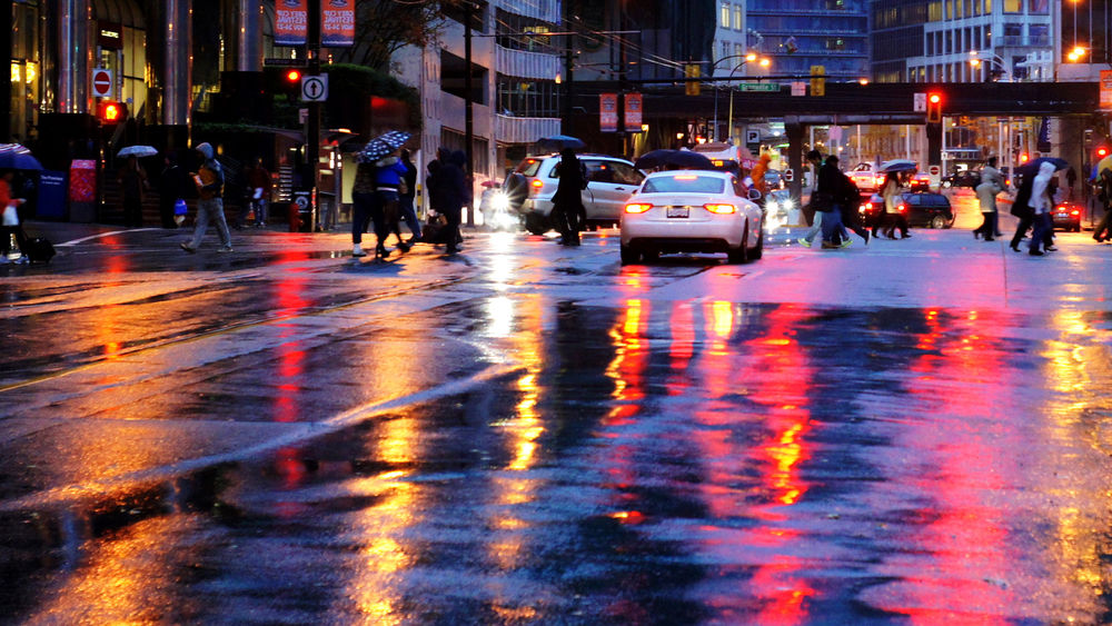 Обои для рабочего стола Городская вечерняя улица после дождя. Блики витрин и огни машин рефлексируют на мокром асфальте