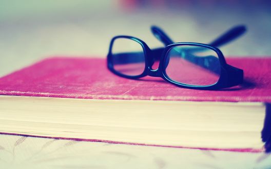 Обои на рабочий стол Очки лежат на книге в розовом переплете