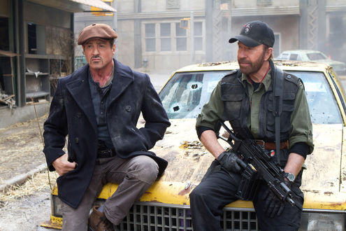 Обои на рабочий стол Сильвестр Сталлоне / Sylvester Stallone и Чак Норрис / Chuck Norris у желтой разбитой машине в разрушенном городе из фильма Неудержимые 2 / The Expendables 2