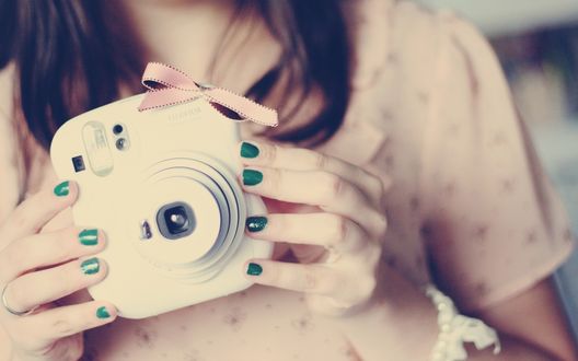 Обои на рабочий стол Девушка держит в руках фотоаппарат марки Fujifilm / Фуджифильм