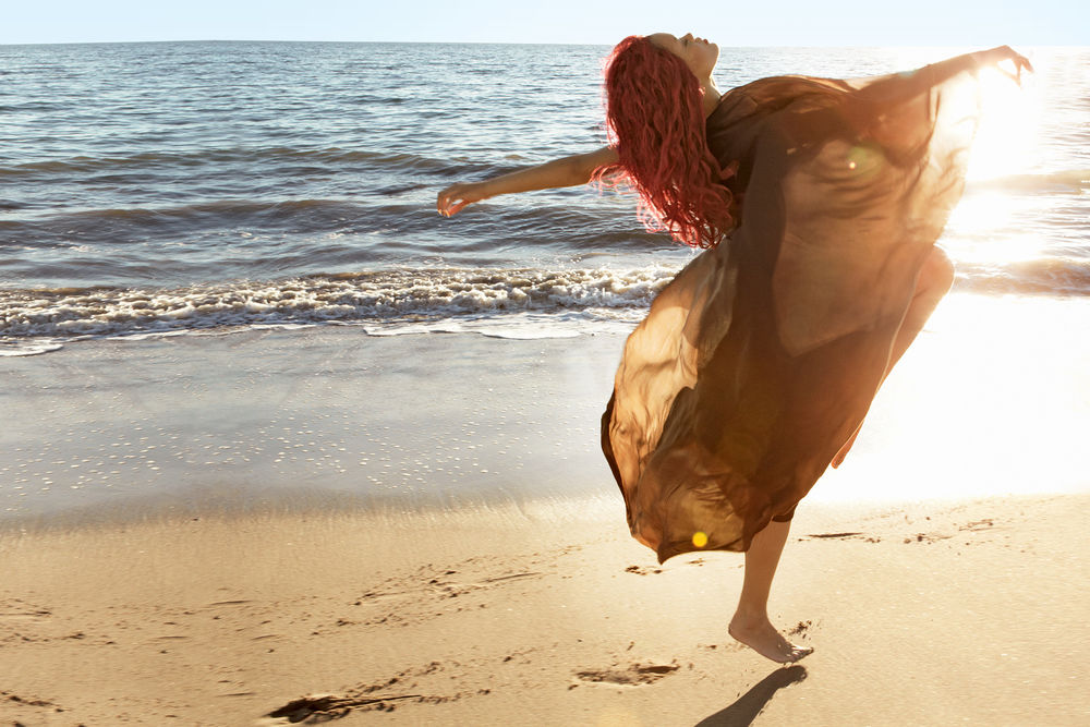 Обои для рабочего стола Певица Рианна / Rihanna танцует в развевающимся платье на фоне океана