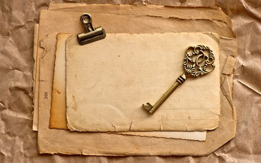 Обои на рабочий стол Старые пожелтевшие страницы, на которых лежит старинный ключ