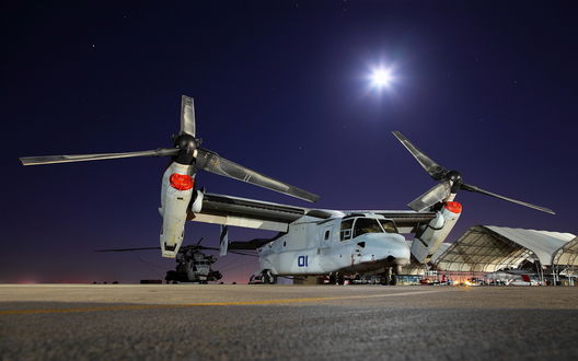 Обои на рабочий стол Американский конвертоплан Bell V-22 Osprey, состоящий на вооружении морской пехоты армии США / USA, стоит на стоянке военного аэродрома на фоне лунного неба