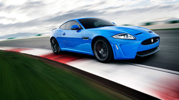 Обои на рабочий стол Автомобиль Jaguar XKR-S синего цвета мчится по гоночной трассе