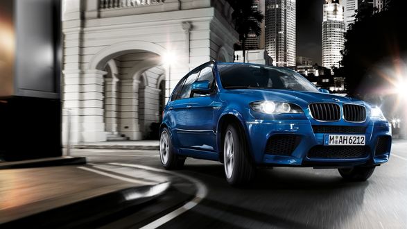Обои на рабочий стол Автомобиль BMW X5 едет по улице ночного мегаполиса
