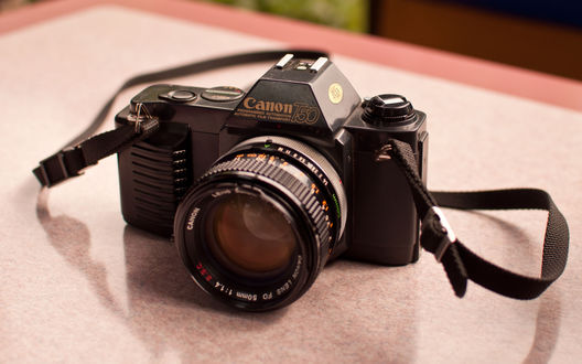 Обои на рабочий стол Фотоаппарат Canon T50 лежит на столе