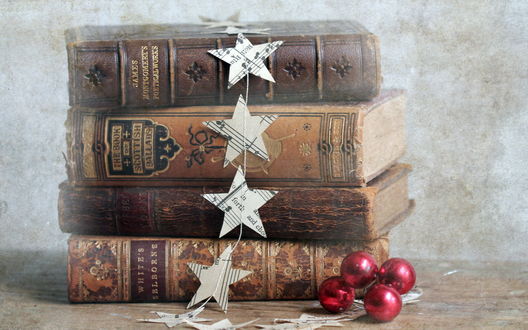 Обои на рабочий стол Старинные книги лежат стопкой, с которой свисают звезды,вырезанные из нот и нанизанные на нитку с лежащими рядом красными шариками