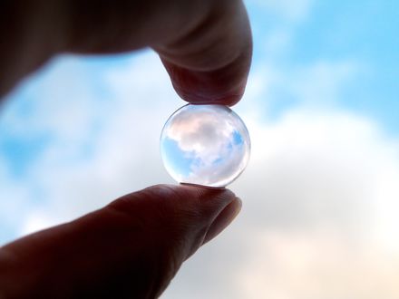 Обои на рабочий стол Прозрачный шар в руке, в котором отражается небо
