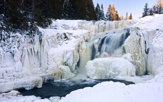 Обои на рабочий стол Водопад с берегами. покрытыми глубоким слоем снега и огромными сосульками
