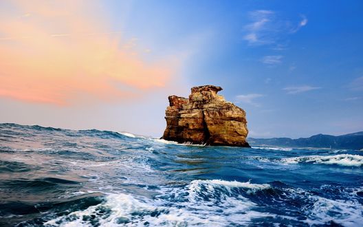 Обои на рабочий стол Красивое скальное образование в прибрежных морских водах на фоне заката