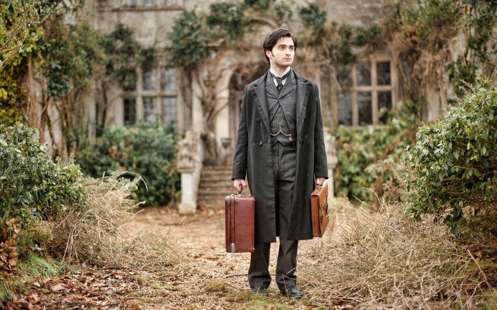 Обои для рабочего стола Дэниел Рэдклифф / Daniel Radcliffe, стоит с двумя чемоданами в руках, позади его дом