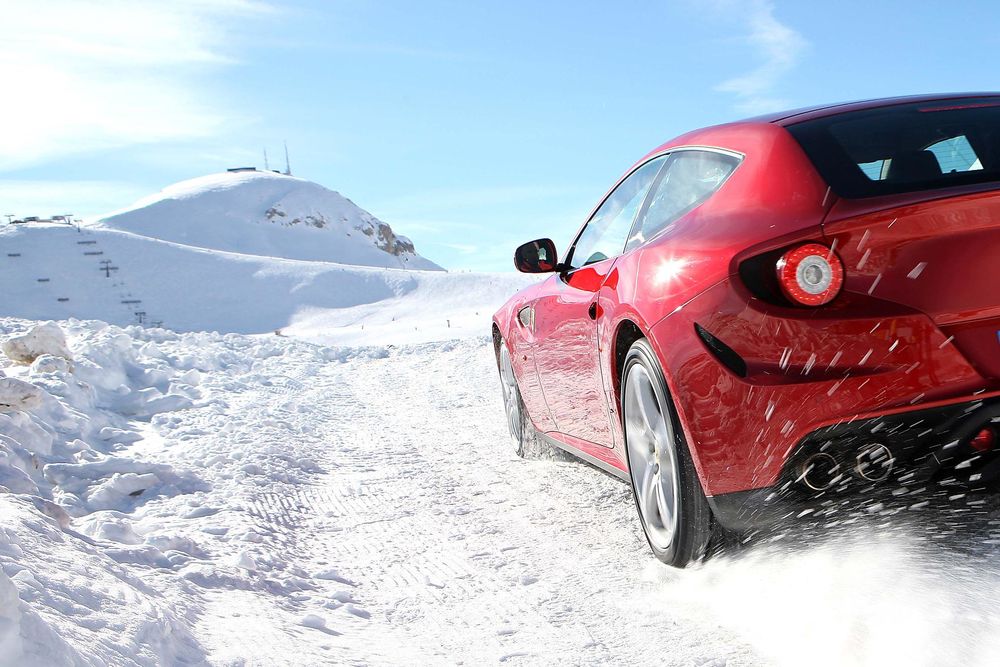 Обои для рабочего стола Ferrari FF / Ферарри ФФ едет по заснеженной горной дороге на фоне чистого голубого неба