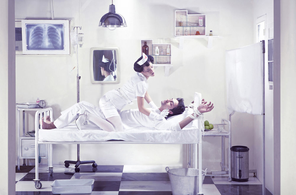 Обои для рабочего стола Медсестра сидит сверху на прокованном к кровати пациенту и собирается ему делать укол