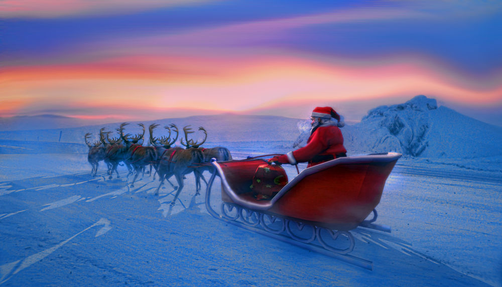 Обои для рабочего стола Дед мороз едет на санях запряженных оленями по снегу на фоне северного неба