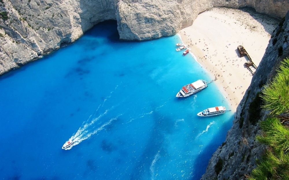 Обои для рабочего стола Вид сверху на морскую бухту на острове Закинф / Zakynthos, Греция / Greece с песчаным пляжем , прогулочными катерами, расположенную между отвесными скалами