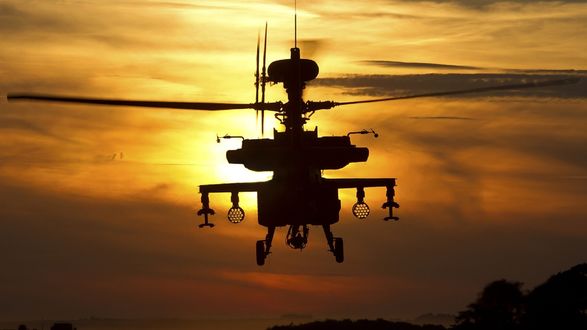 Обои на рабочий стол Американский вертолет Ан-64 'Апач / Apache' совершает полет на фоне заката солнца