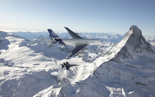 Обои на рабочий стол Пассажирский самолет Аэробус А-380 / Airbus A-380 совершает демонстрационный полет над заснеженными горами в сопровождении боевого истребителя
