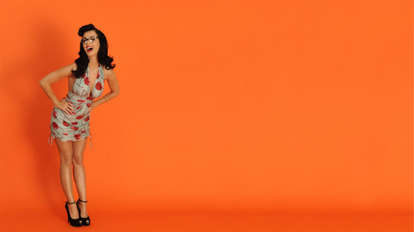 Обои на рабочий стол Американская певица Кэти Перри / Katy Perry стоит на ярко-оранжевом фоне