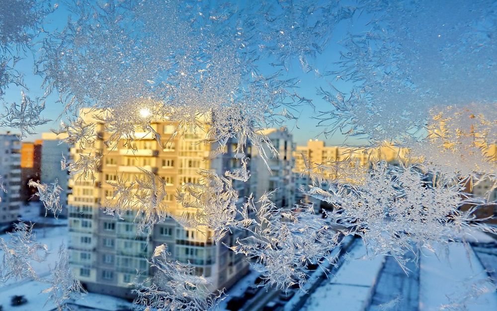 Обои для рабочего стола Ледяные узоры на окне с видом на город