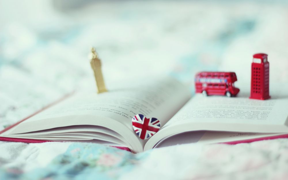 Обои для рабочего стола Раскрытая книга, на которой лежат статуэтки красного автобуса, красной телефонной будки и Биг Бена / Big Ben, символов города Лондона / London и сердечко, раскрашенное как флаг Великобритании / Great Britain