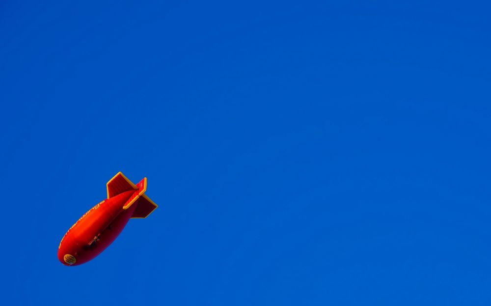 Обои для рабочего стола Красный дирижабль на фоне голубого неба