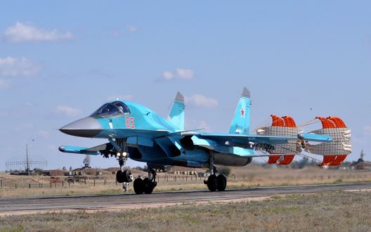 Обои на рабочий стол Многоцелевой истребитель Российских ВВС Су-34 производит посадку на бетонную взлетно-посадочную полосу с выпущенными тормозными парашютами