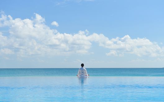 Обои на рабочий стол Мужчина в позе лотоса медитирует на море