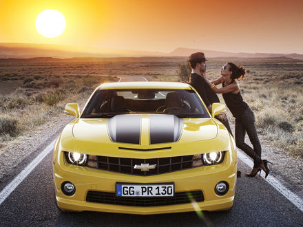 Обои на рабочий стол Желтый Chevrolet Camaro / Шевроле Камаро стоит на дороге, возле машины стоят мужчина и девушка