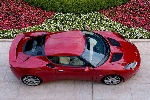 Обои на рабочий стол Lotus Evora / Лотус Эвора 2010 (Wine color Metallic), у цветочной клумбы