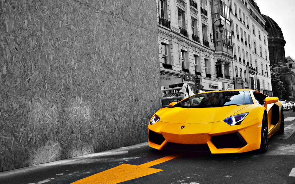 Обои для рабочего стола Автомобиль Ламборджини Авентадор / Lamborghini Aventador желтого цвета на фоне здания