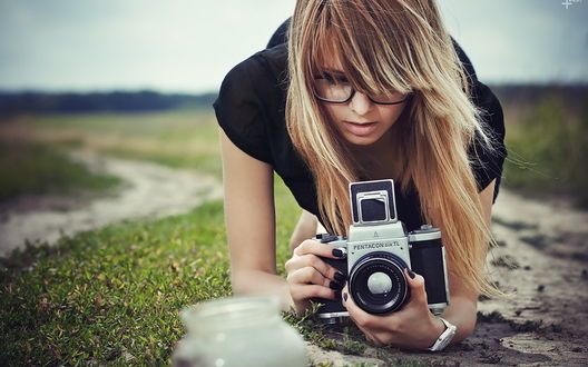 Обои на рабочий стол Девушка с фотоаппаратом лежит на земле