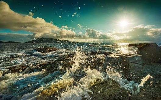 Обои на рабочий стол Бьющиеся о камни морские волны в свете солнца