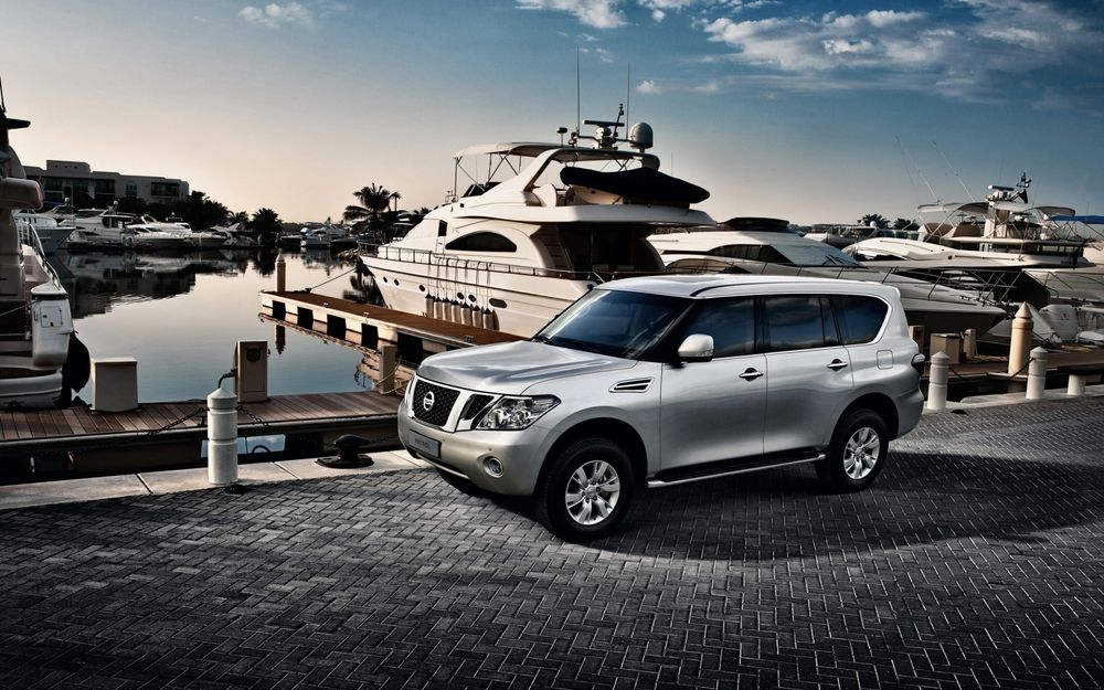 Обои для рабочего стола Nissan Patrol серебристого цвета стоит на пристани на фоне яхт