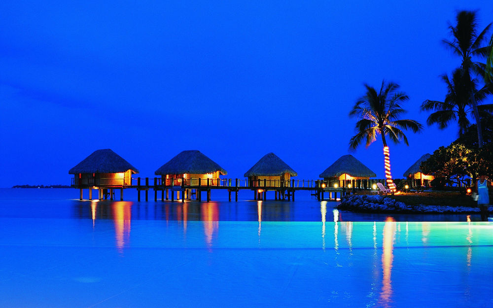 Обои для рабочего стола Бунгало отеля Manihi Pearl Beach Resort 4 во Французской Полинезии / French Polynesia с освещением на пальмах в вечернее время суток