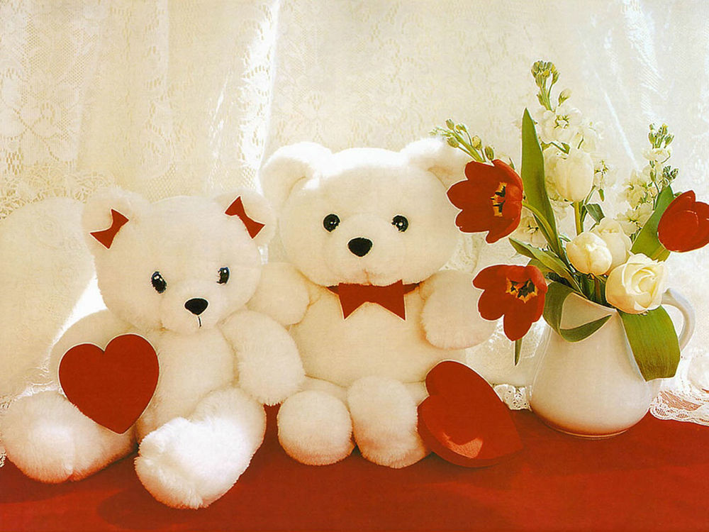 Обои для рабочего стола Два белых плюшевых медведя с красными сердечками сидят на столе, а рядом с ними стоит ваза с цветами
