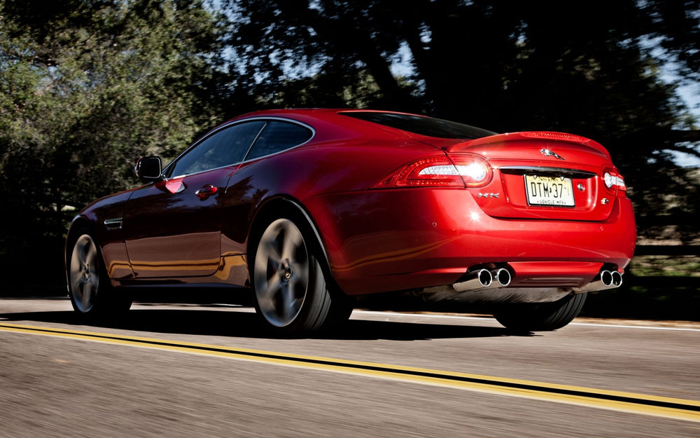 Обои для рабочего стола Красный автомобиль Jaguar XKR / Ягуар XKR купе мчится по дороге