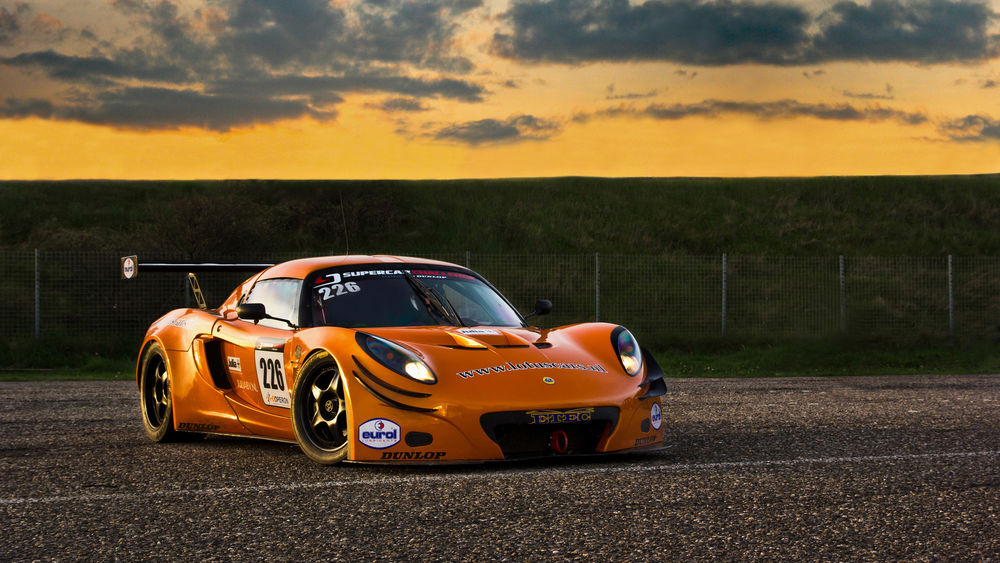 Обои для рабочего стола Оранжевый автомобиль Lotus Sport Exige GT3 / Лотус стоит поперек дороги