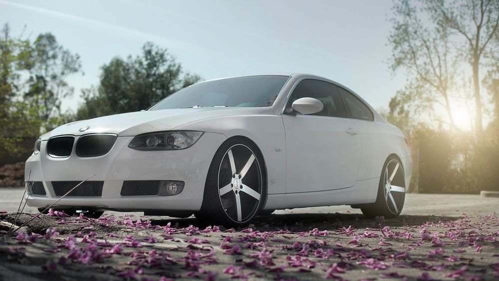 Обои для рабочего стола Белый автомобиль BMW 3 E92 / БМВ стоит возле светло - фиолетовых лепестков