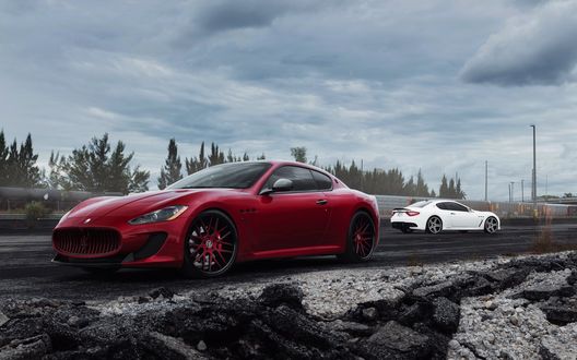 Обои на рабочий стол Красная и белая машины Maserati GranTurismo / Мазерати ГранТуризмо стоят на дороге, на фоне деревьев и облаков