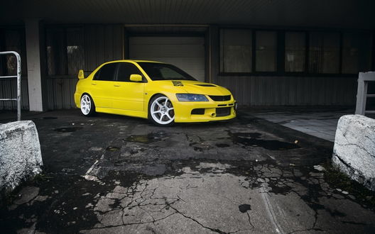 Обои на рабочий стол Желтое авто Mitsubishi Lancer Evolution / Мицубиcи Лансер Эволюшн стоит у дома