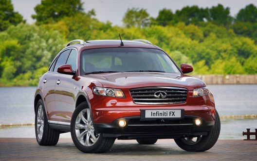 Обои на рабочий стол Красное авто Infiniti FX на фоне деревьев стоит у воды
