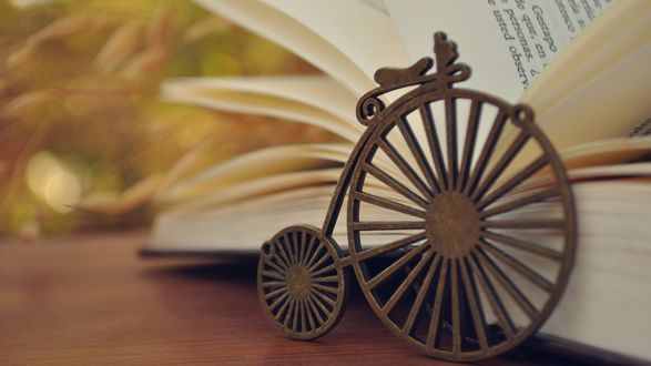 Обои на рабочий стол Украшение в виде колес кареты и раскрытая книга