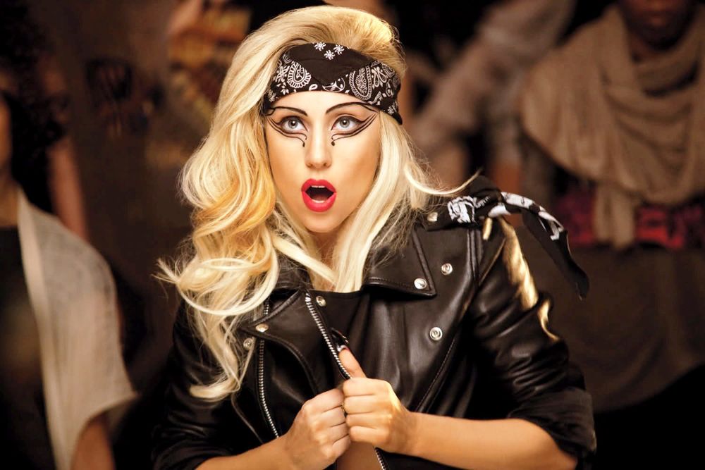 Обои для рабочего стола Американская певица Lady Gaga / Леди Гага в кожаной куртке и с повязкой на лбу удивленно смотрит на кого-то