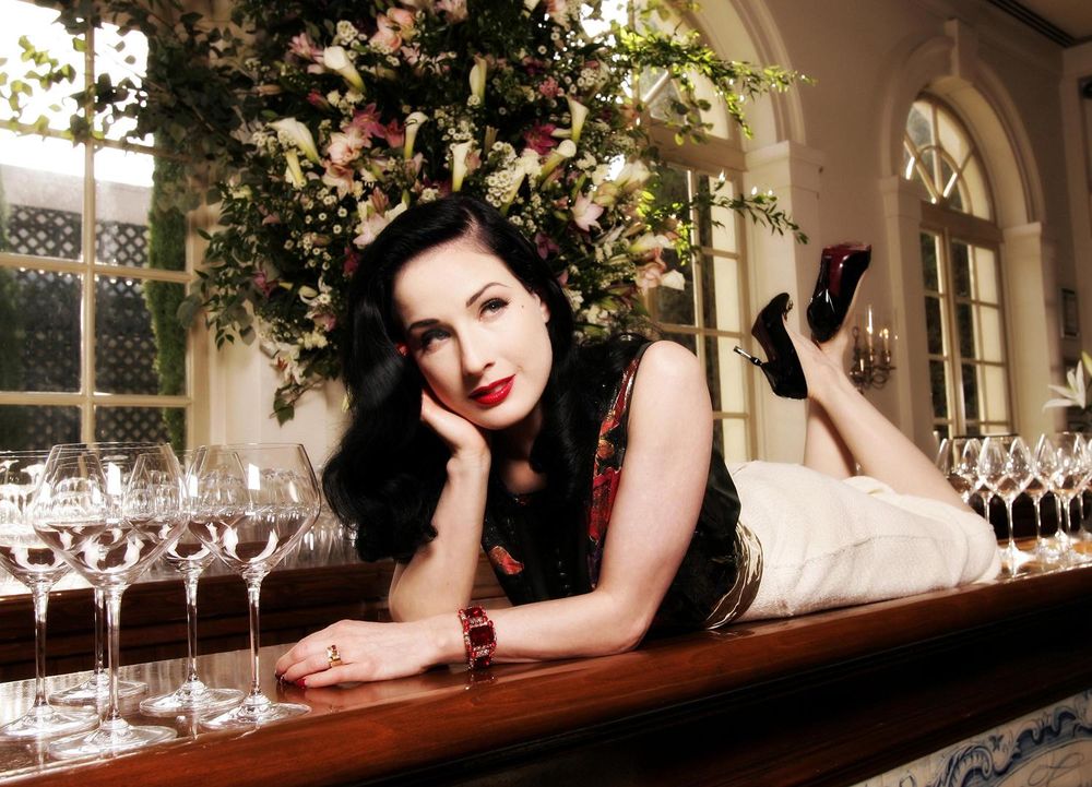 Обои для рабочего стола Dita Von Teese / Дита фон Тиз лежит на барной стойке, смотря куда-то