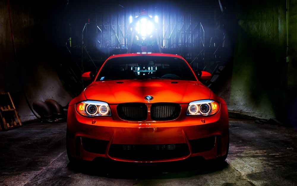 Обои для рабочего стола Красная машина марки BMW 1M стоит в подвальном помещении